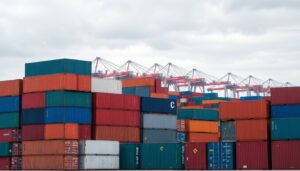 Stacked shipping containers and gantry cranes at a port terminal